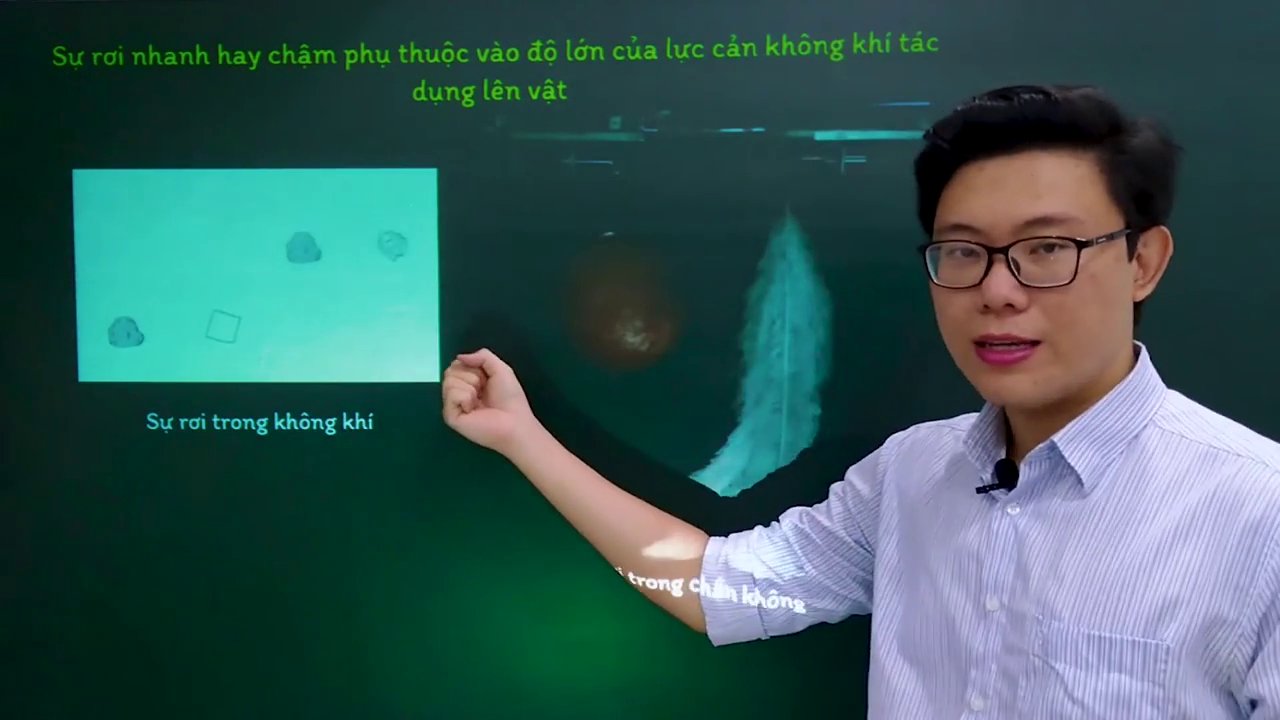 Giáo viên đang chỉ vào hình minh họa trên bảng về sự rơi của các vật thể trong không khí và chân không.